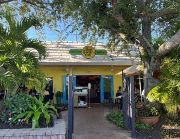 Cafe exterior with entrance gate surrounded by greenery
