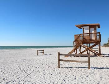 A lifeguard stand and wide-open sand on a clear day at Coquina Beach