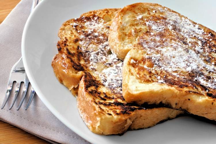 Plate with two slices of French toast covered in powdered sugar