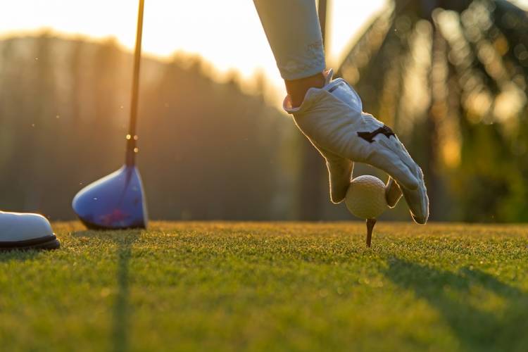 Golfer setting golf ball on tee