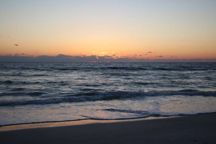 Waves and clouds seen from the shoreline at Manatee Beach at sunset