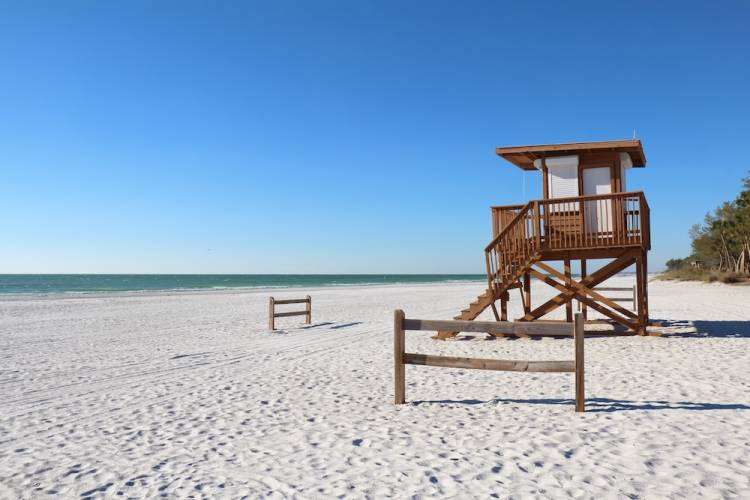 A lifeguard tower and wide-open sand on a clear day at Coquina Beach