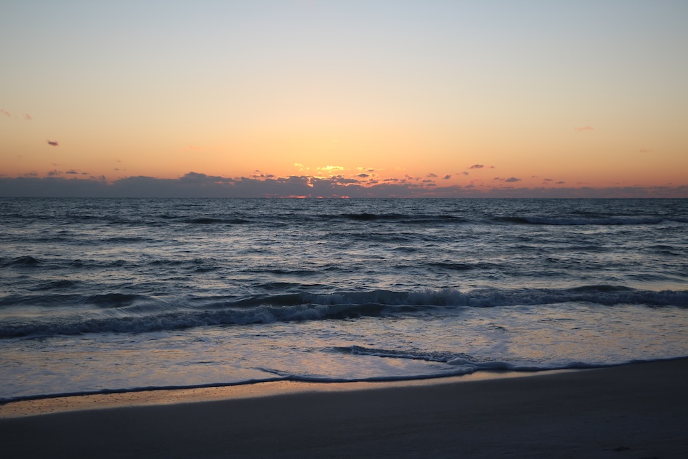 Waves and clouds seen from the shoreline at Manatee Beach at sunset