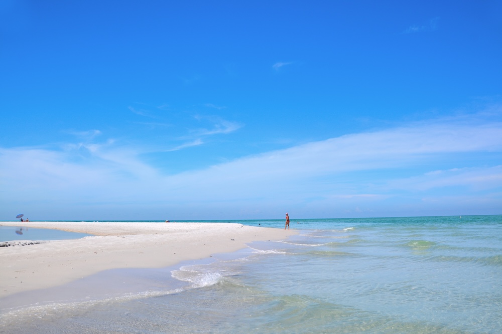 A woman walking along the Anna Maria Island shoreline on a clear day