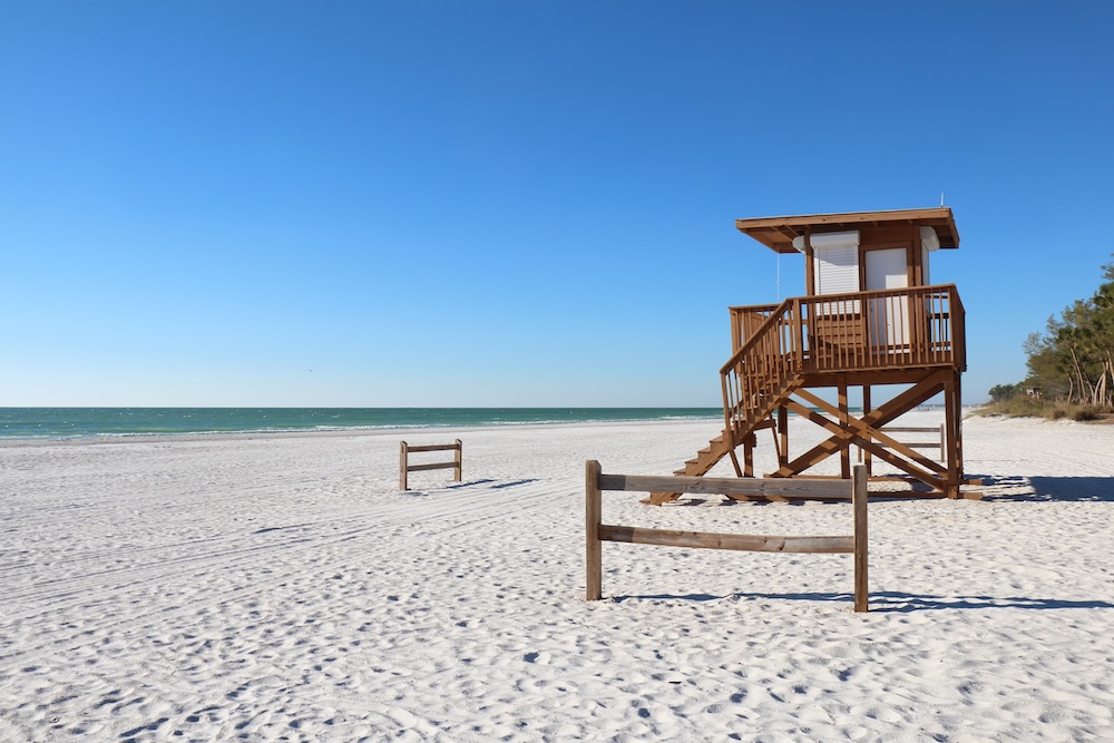 A lifeguard stand and wide-open sand on a clear day at Coquina Beach